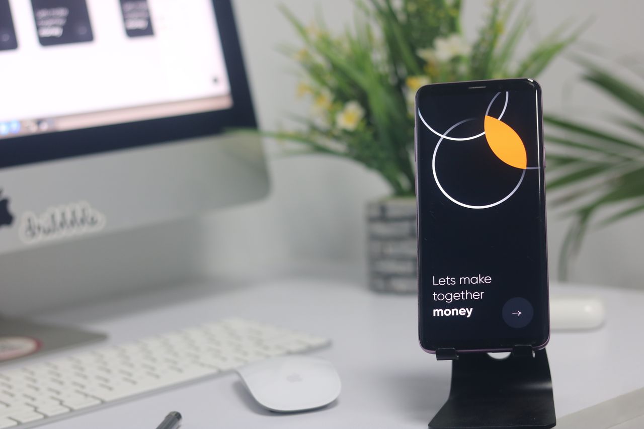 Un espace de travail moderne avec un smartphone affichant un écran et une configuration informatique, idéal pour des thèmes liés aux affaires et à la technologie.